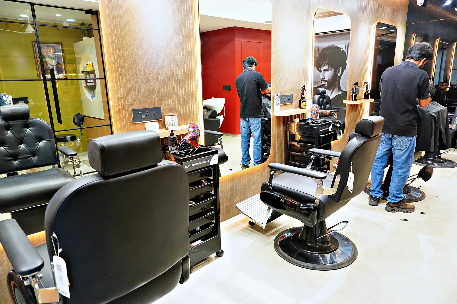 Row of black barber chairs, mirrors and a red accent wall