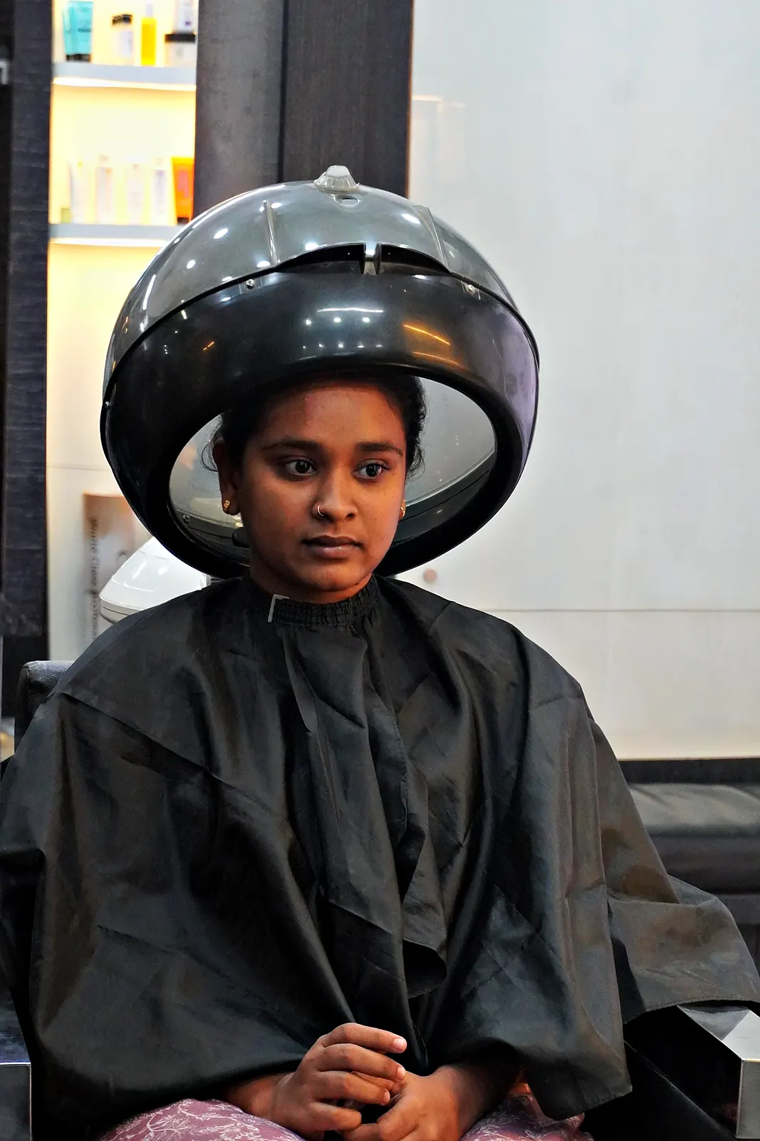 Client relaxing under the hair steamer